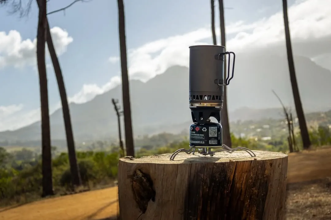 The Argo Multistand under a gas canister and pot on a tree stump, mountains behind